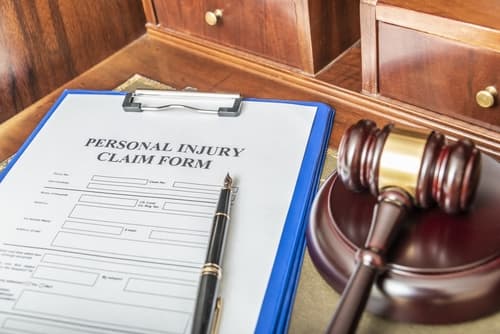 personal injury claim form in clipboard on desk with gavel