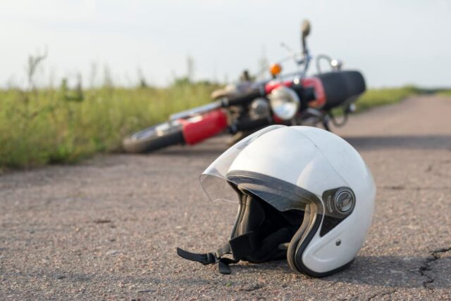 motorcycle helmet and bike on the road, symbolizing the risk and aftermath of road accidents.