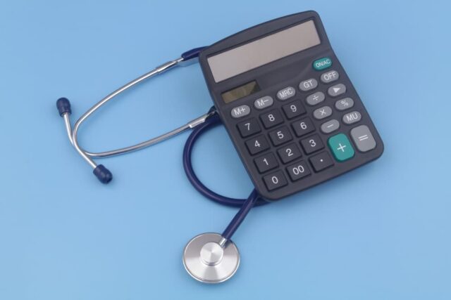 Stethoscope and black calculator on blue background. Cost of medicine and medical insurance concept.